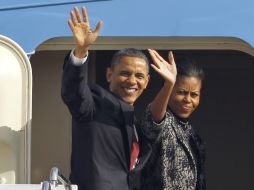 Barack y Michelle Obama saludan desde la pueta del avión presidencial Air Force One, antes de partir rumbo a San Diego. AP  /