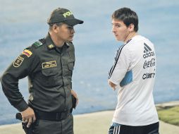 Lionel Messi (der.) pasa junto a un policía colombiano en su camino al campo de entrenamiento de la albiceleste. AFP  /