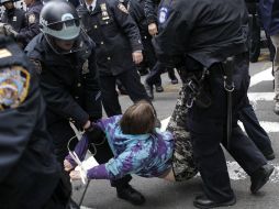 Policías cargan a un detenido para llevarlo a una patrulla. AP  /