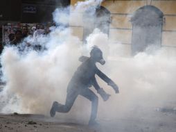 Un jóven egipcio corre entre el humo de gas lacrimógeno durante los enfrentamientos. EFE  /