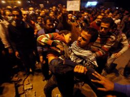 Un manifestante carga a un joven herido durante los enfrentamientos con policías en la plaza Tahrir, en El Cairo. AP  /
