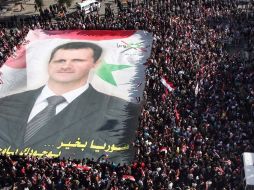 Manifestantes simpatizantes del gobierno muestran un cartel gigante del presidente sirio, Bachar al Asad. EFE  /