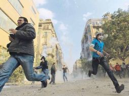 Manifestantes egipcios huyen de los gases lacrimógenos utilizados por las Fuerzas Armadas en El Cairo para disolver las protestas. AFP  /