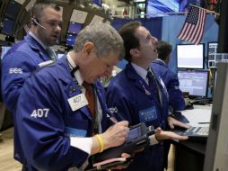 El especialista Glenn  Carell (D) trabaja en su puesto en el piso de la Bolsa de Nueva York. AP  /