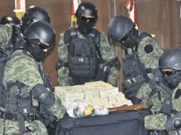 Elementos del Ejército cargan la mesa llena de dólares para mostrarla a la prensa. EFE  /
