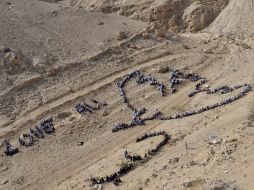 Los niños recrean la imagen de la paloma de la paz inspirada en la obra de Picasso hoy en Jericó. EFE  /