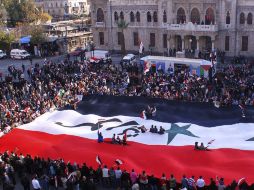 Los manifestantes en el centro de Damasco sujetando una enorme bandera siria en apoyo del dirigente Bachar el Asad. EFE  /