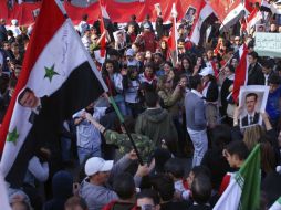 Varias personas muestran banderas y carteles con la imagen del dirigente sirio Bachar el Asad en Damasco. EFE  /