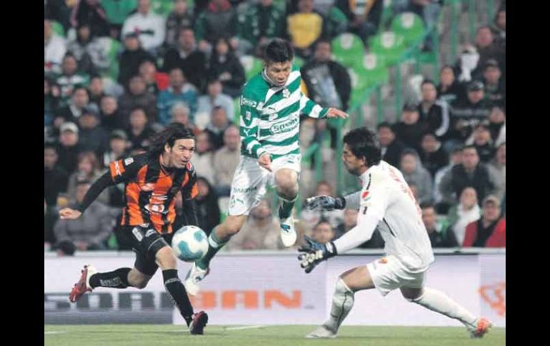 Oribe Peralta (centro) dispara ante la salida del portero Édgar Hernández (der.) y la marca de Gerardo Espinoza. MEXSPORT  /