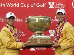 Matt Kuchar y Gary Woodland levantan el trofeo de la Copa Mundial de Golf. AP  /
