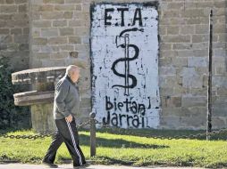 Un hombre pasa frente a una pared con una leyenda de la ETA, en Arbizu. AP  /