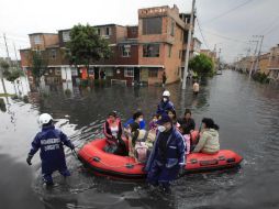 Bomberos evacúan en lancha a un grupo de habitantes. AP  /