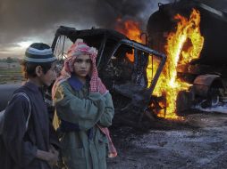 Unos niños observan los autobuses en llamas. REUTERS  /