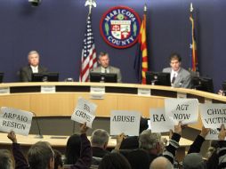 Ciudadanos de Maricopa portan carteles que piden la renuncia de Arpaio en una sesión del congreso local. AP  /