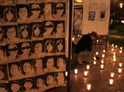 Un hombre  enciende velas junto a  un cartel con imágenes de personas que desaparecieron durante el régimen de Fujimori. REUTERS  /