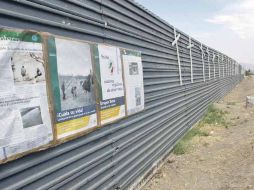 Vista de la barda que divide Estados Unidos con México, donde se aprecian diversos carteles preventivos para migrantes.  /