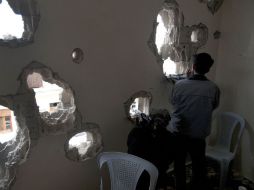 Soldados sirios desertan y cambian la posición de sus fusiles  detrás de una pared de una casa dañada en la zona de Baba Amr. AP  /