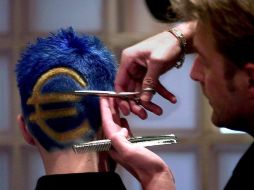 Un peluquero pinta el cabello y lo corta  con el logo del euro, en Deinze, Bélgica. EFE  /