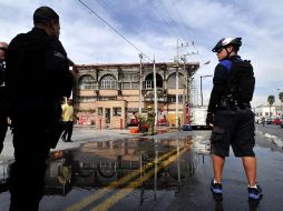 Agentes municipales resguardan el sitio mientras bomberos trabajan en el edificio para evitar que se reaviven las llamas. EFE  /