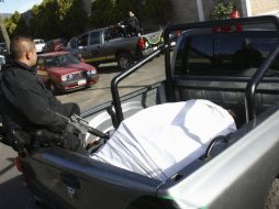 Agentes estatales resguardan los cuerpos de 13 personas asesinadas en la madrugada de hoy en Michoacán. EFE  /