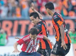 ''Cubo'' Torres, de Chivas, trata de avanzar ante la marca de dos defensas chiapanecos. MEXSPORT  /