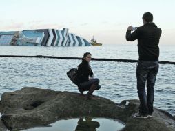 Personas toman una foto sobre una roca frente al ''Costa Concordia''. REUTERS  /