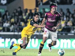 El volante de Estudiantes, Gabriel Pereyra (der.) conduce el esférico ante la marca del jugador del América, Jesús Molina. EFE  /