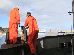 Trabajadores preparan maquinaria para limpiar el combustible derramado de los tanques del crucero. EFE  /