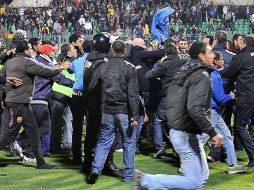 Aficionados se enfrentan en el campo de juego mientras otros corren. AFP  /