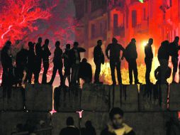 Manifestantes esperan a los policías para atacarlos con piedras, en El Cairo. AP  /