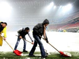 Empleados del Inter de Milán retiran nieve del terreno de juego en el estadio Giuseppe Meazza. EFE  /