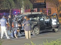 Expertos forenses trabajan en el vehículo en el que emprendieron la fuga tres sospechosos, en el municipio de Zapopan.  /