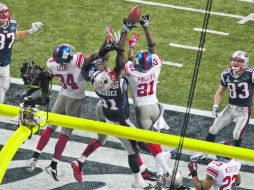 Aaron Hernández (centro), intenta atrapar el último pase ante la marca de los defensivos de Gigantes. REUTERS  /