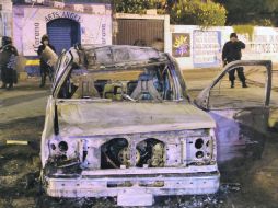 Un agente observa la  camioneta calcinada en la que viajaban los tres supuestos plagiarios. EFE  /
