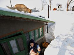 Un gato observa desde el tejado las tareas de su dueña tras despejar la entrada de su casa. EFE  /