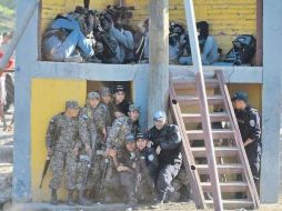 Policías y reporteros se protegen de las pedradas que lanzaban familiares de los internos. AP  /