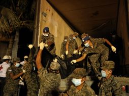 Los soldados suben los cuerpos a un camión para trasladarlos. AFP  /