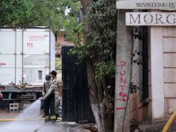 Empleados del Instituto médico forense de Honduras lavan la entrada de donde se tiene los cuerpos de la tragedia de Comayagua. AFP  /
