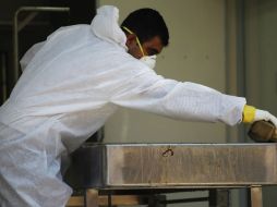 Un miembro del equipo forense en Comayagua limpia la camilla donde revisan los restos de los fallecidos. REUTERS  /