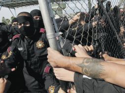 TENSIÓN.- Familiares de los internos forcejean con los elementos de seguridad. AFP  /