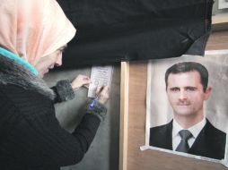 Una mujer emite su voto sobre el nuevo referéndum constitucional de Siria, frente a una imagen del presidente Bashar al Assad. AFP  /
