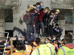 Protestantes intentan mantener su posición mientras uno es jalado por los policías que lo esperan debajo.  /