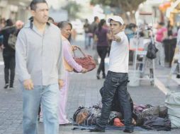 Un vendedor irregular saluda mientras atiende a un cliente, en el Centro tapatío.  /