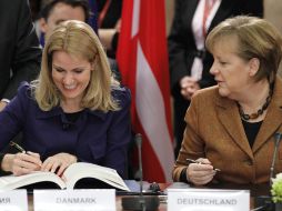 La canciller alemana, Angela Merkel (d), y la primera ministra danesa, Helle Thorning Schmidt (i), firman el pacto. EFE  /