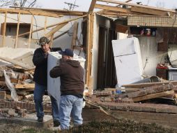 Dos hombres cargan con un mueble intentando salvar lo que ha quedado de su casa arrasada por un tornado en la ciudad de Henryville. EFE  /
