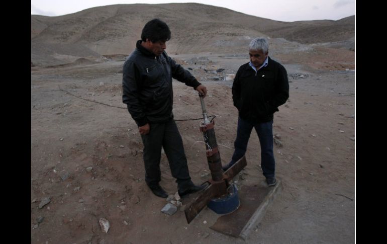 Dos mineros que sobrevivieron al accidente de 2010 muestran la sonda a través de la que recibían alimentos. ARCHIVO  /