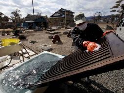 Un hombre lava la puerta de su hogar para tratar de descontaminarla, esto en la localidad de Hirono, cerca de Fukushima. AP  /