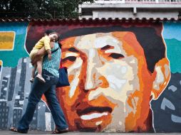 Una muje pasa junto a un mural con el retraro de Chávez, quien anunció su regreso a Caracas esta semana. EFE  /