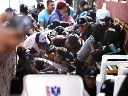 Los jugadores de Saraperos de Saltillo y aficionados se resguardan tras la balacera cerca del estadio. AP  /