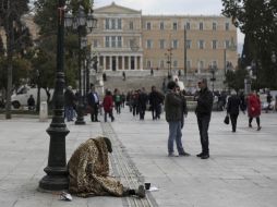 Una persona indigente pide limosna en una plazoleta frente al Parlamento griego. AP  /